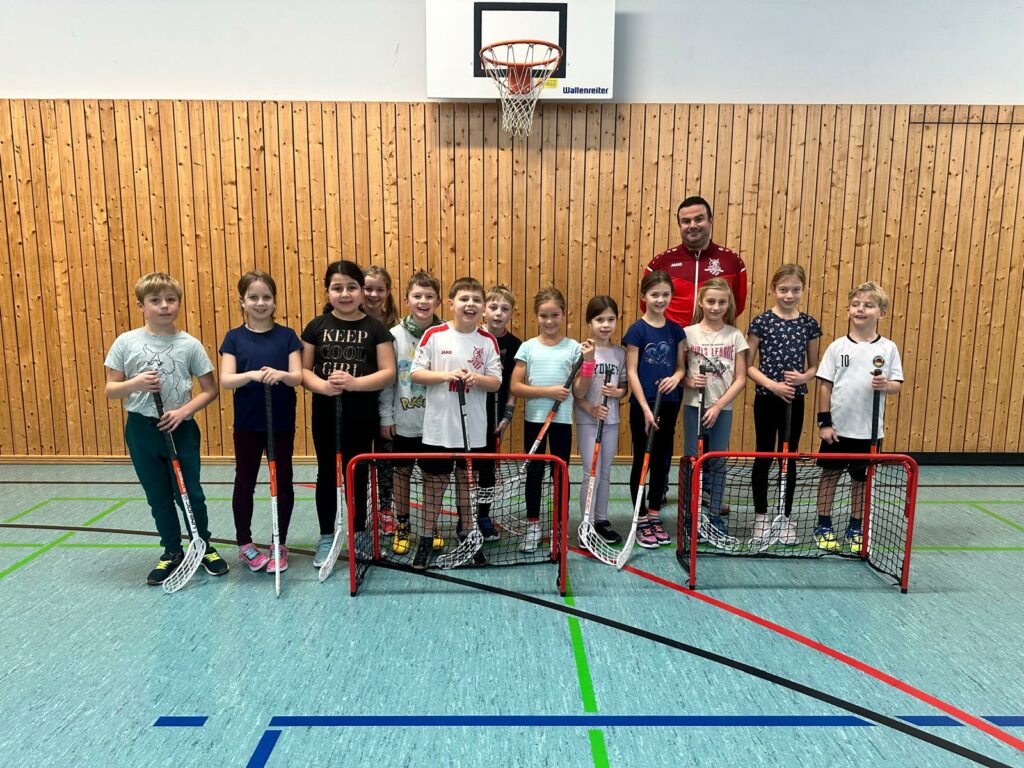 Kinder mit Floorballschlägern vor zwei kleinen Toren